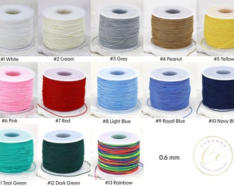 Puede incluir: Una colección de 13 carretes de cordón elástico de 0,6 mm de diámetro, en varios colores, incluyendo blanco, crema, gris, cacahuete, amarillo, rosa, rojo, azul claro, azul real, azul marino, verde azulado, verde oscuro y arcoíris. Los carretes están dispuestos en tres filas de cuatro, con la última fila que tiene solo tres carretes. El texto "0,6 mm" está impreso debajo de los carretes.