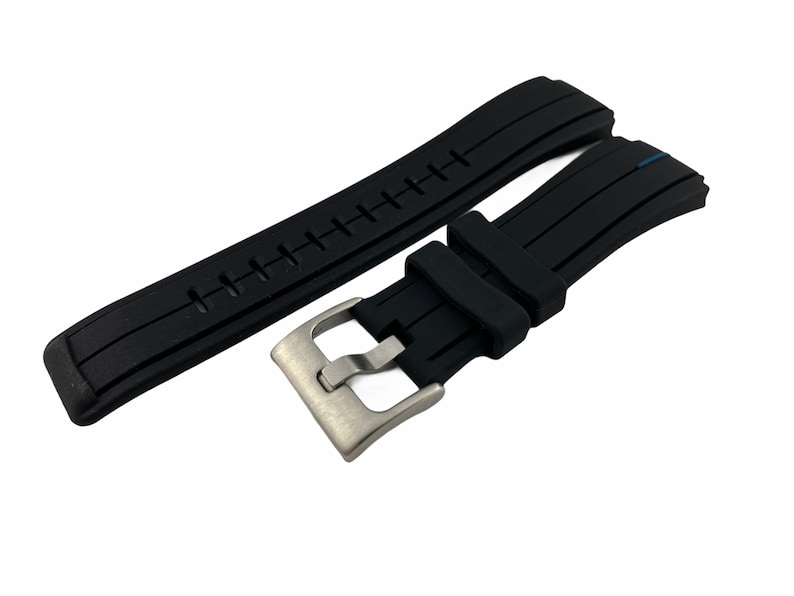 May include: Black silicone watch strap with a stainless steel buckle. The strap has a textured surface and a blue accent.