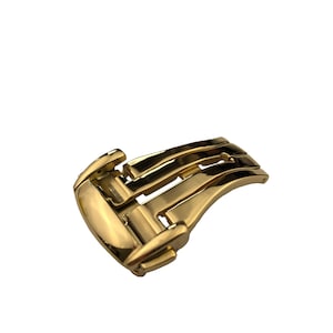 May include: A gold-toned metal watch band buckle with a deployment clasp.