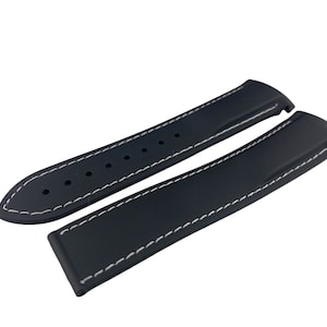 May include: Two black watch straps with white stitching. The straps are made of rubber and have a smooth finish.