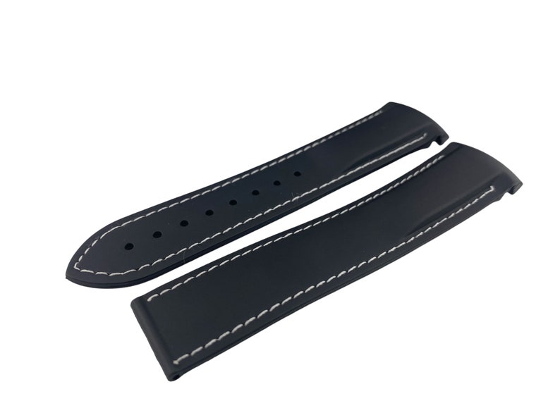 May include: Two black watch straps with white stitching. The straps are made of rubber and have a smooth finish.