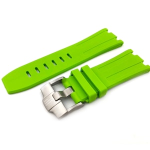 May include: A bright green rubber watch strap with a stainless steel buckle. The strap has a textured surface and multiple holes for adjusting the fit.
