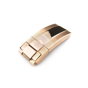 K&ouml;nnte beinhalten: Ein goldfarbener Uhrenarmbandverschluss mit polierter Oberfl&auml;che.