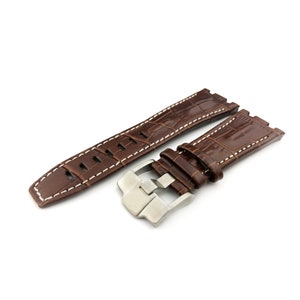 May include: A brown leather watch strap with white stitching and a silver buckle.