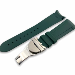 May include: A dark green rubber watch strap with a silver buckle. The strap is designed for a watch with a lug width of 20mm.