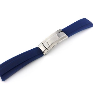 Peut inclure: Un bracelet de montre en caoutchouc bleu avec une boucle argentée.