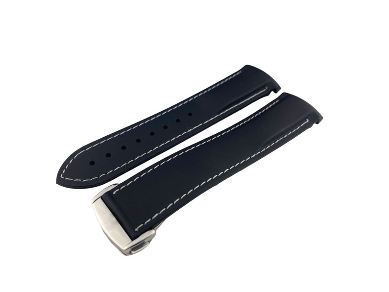 May include: Black rubber watch strap with white stitching and a silver buckle.