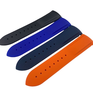Może przedstawiać: Cztery paski do zegarka w r&oacute;żnych kolorach: czarny, niebieski, ciemnoniebieski i pomarańczowy. Paski są wykonane z gumy i mają fakturowaną powierzchnię.