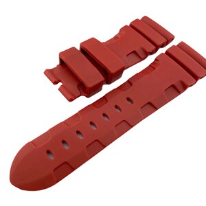 May include: A red rubber watch strap with a textured design and a buckle.