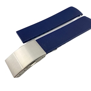May include: A blue rubber watch strap with a silver buckle. The strap has a textured surface.