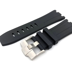 May include: Black rubber watch strap with a silver buckle. The strap has a textured surface and is designed for a watch with a lug width of 22mm.