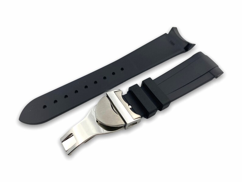 K&ouml;nnte beinhalten: Schwarzes Kautschuk-Armband mit einer silbernen Schlie&szlig;e. Das Armband hat eine strukturierte Oberfl&auml;che und ist f&uuml;r eine Uhr mit gebogenen Anst&ouml;&szlig;en konzipiert.