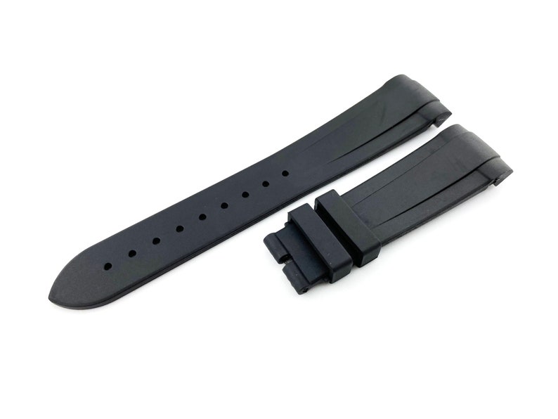 K&ouml;nnte beinhalten: Schwarzes Kautschuk-Armband mit einer Schlie&szlig;e. Das Armband hat eine strukturierte Oberfl&auml;che und ist f&uuml;r eine Uhr mit einer Bandansto&szlig;breite von 22 mm ausgelegt.