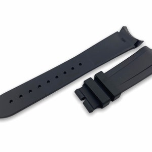 K&ouml;nnte beinhalten: Schwarzes Kautschuk-Armband mit einer Schlie&szlig;e und L&ouml;chern zum Einstellen der Gr&ouml;&szlig;e.