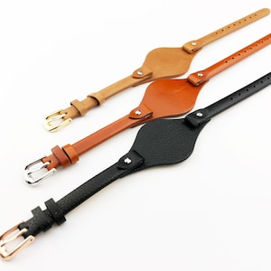 May include: Three leather watch bands with different colored straps and buckles. The bands are brown, tan, and black.