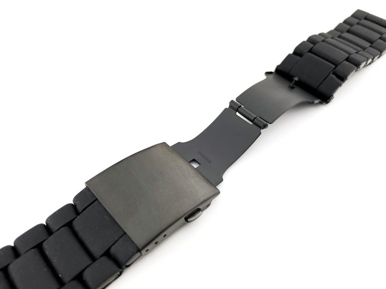 May include: Black watch strap with a metal buckle. The strap is made from a rubber-like material and has a matt finish.