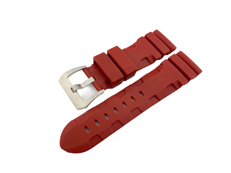 May include: A red silicone watch strap with a silver buckle. The strap has a textured design and is designed for a watch with a 22mm lug width.