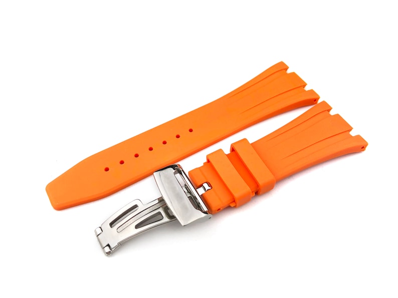 May include: Orange rubber watch strap with a silver buckle. The strap has a textured design and is made of high-quality rubber.