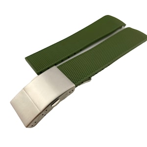 May include: A green rubber watch strap with a silver buckle. The strap has a textured surface.