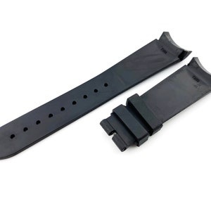 K&ouml;nnte beinhalten: Schwarzes Kautschuk-Armband mit zwei schwarzen Schlie&szlig;en. Das Armband hat eine strukturierte Oberfl&auml;che und ist an beiden Enden mit "T390" gekennzeichnet.