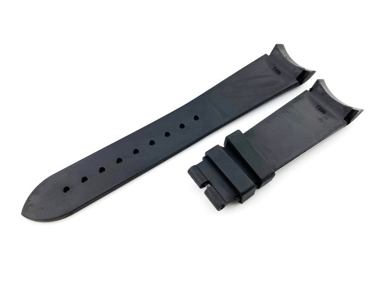 K&ouml;nnte beinhalten: Schwarzes Kautschuk-Armband mit zwei schwarzen Schlie&szlig;en. Das Armband hat eine strukturierte Oberfl&auml;che und ist an beiden Enden mit "T390" gekennzeichnet.