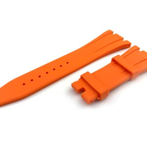 May include: Orange rubber watch strap with a textured design and a buckle fastening.