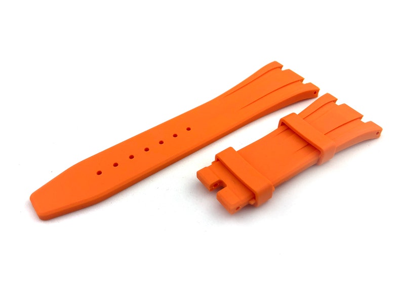 May include: Orange rubber watch strap with a textured design and a buckle fastening.