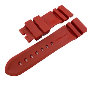 May include: Red rubber watch strap with a buckle and the text "SWISS MADE" printed on the strap.
