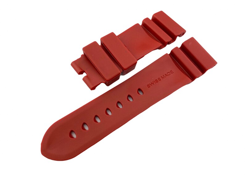 May include: Red rubber watch strap with a buckle and the text "SWISS MADE" printed on the strap.