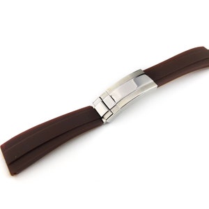 May include: A brown rubber watch strap with a stainless steel buckle.