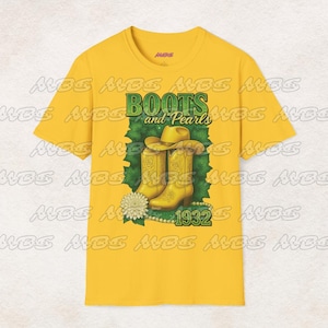 Può includere: Maglietta gialla con una grafica verde e bianca di stivali da cowboy e perle. Il testo "Boots and Pearls" e "1932" sono sulla grafica.