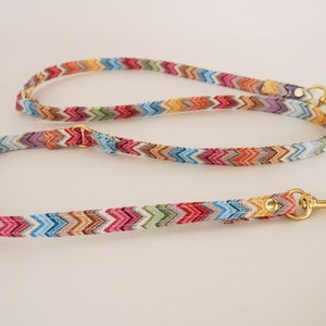 May include: A colorful zig-zag patterned dog leash with gold hardware and two clips.