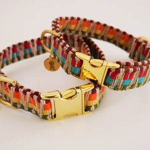 May include: Two colorful dog collars with gold-tone hardware. The collars are woven with red, orange, yellow, green, blue, and brown threads. The collars have gold-tone buckles and D-rings.