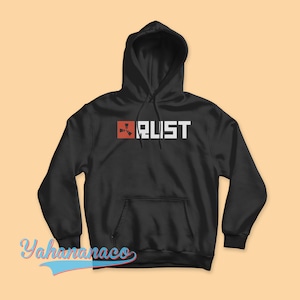 Puede incluir: Sudadera con capucha negra con un logotipo de Rust rojo y blanco en la parte delantera. El logotipo presenta un símbolo estilizado y la palabra "Rust" en letras blancas.