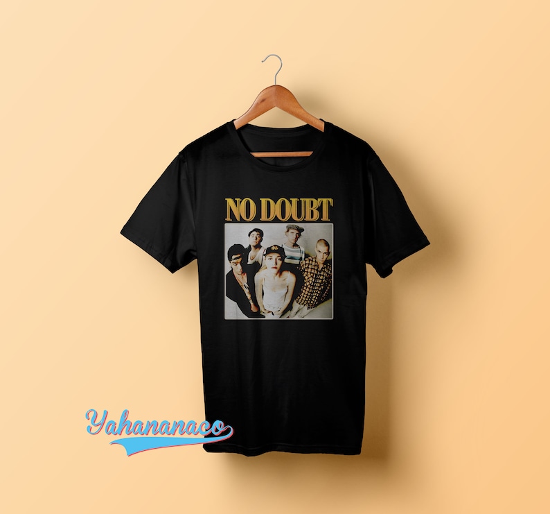 May include: Black t-shirt with a vintage photo of the band No Doubt. The band members are all wearing casual clothing and are looking at the camera. The text "NO DOUBT" is printed in gold letters above the photo.