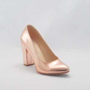 May include: Rose gold high-heeled pumps with a thick block heel.