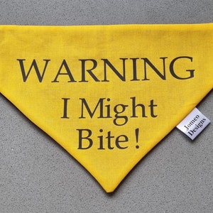 May include: Yellow dog bandana with black text that reads "WARNING I Might Bite!" and a white tag that reads "Jomeo Designs".