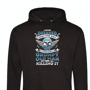 Può includere: Felpa con cappuccio nera con una stampa grafica di un teschio con una bandana e la barba. Il testo recita "Non ho mai sognato che un giorno sarei diventato un vecchio brontolone, ma eccoci qui, sto uccidendolo".