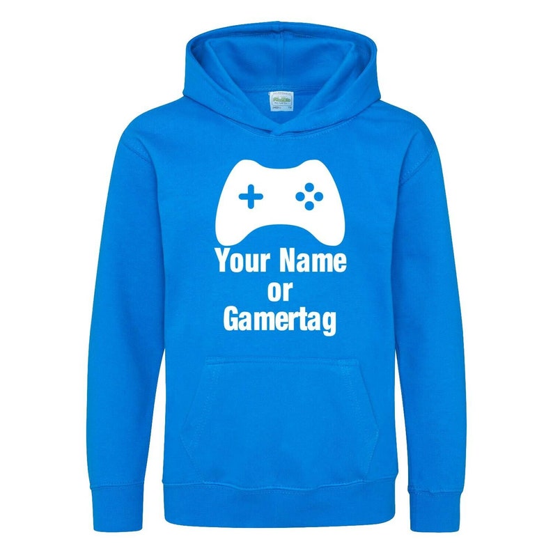 以下が含まれることがあります： 白いビデオゲームコントローラーのグラフィックと「Your Name or Gamertag」というテキストが書かれた明るい青色のフード付きスウェットシャツです。