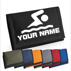 Può includere: Portafoglio nero a tre pieghe con una silhouette di nuotatore bianca e il testo "YOUR NAME". Il portafoglio è mostrato con altre opzioni di colore: verde, blu, arancione, grigio, rosso e blu reale.