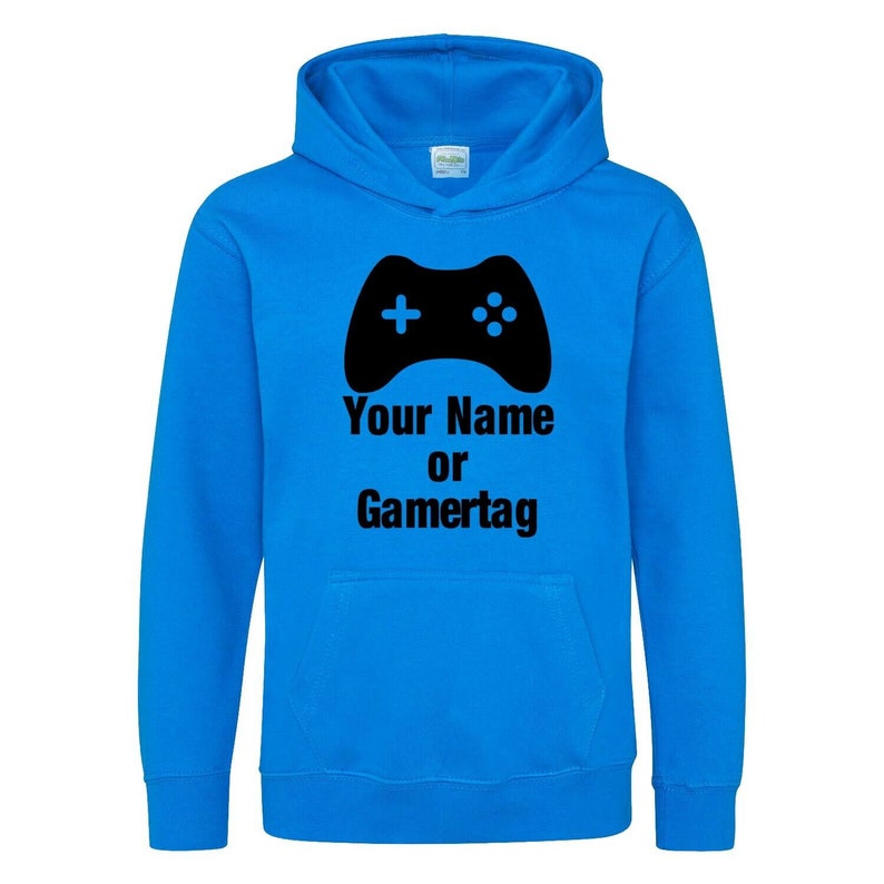 以下が含まれることがあります： 黒いビデオゲームコントローラーのグラフィックと「Your Name or Gamertag」というテキストが書かれた明るい青色のフード付きスウェットシャツです。