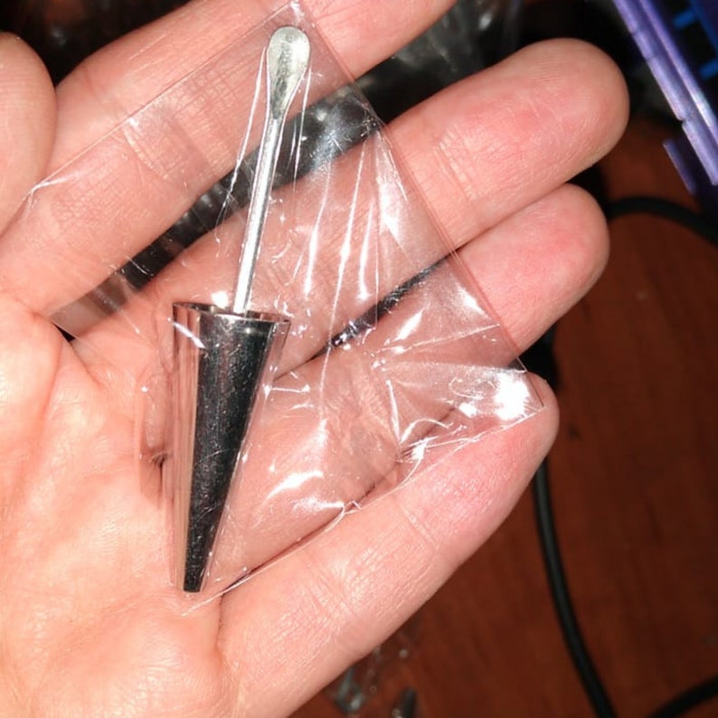 Puede incluir: Una herramienta de metal plateado con una punta puntiaguda y una peque&ntilde;a pala en el extremo. La herramienta est&aacute; empaquetada en una bolsa de pl&aacute;stico transparente.