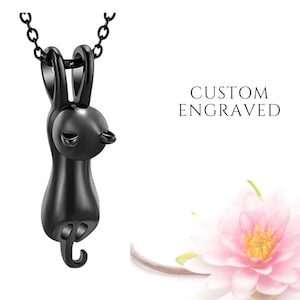 May include: A black pendant necklace featuring a small, detailed rabbit charm. The charm is hanging from a delicate black chain. The text "CUSTOM ENGRAVED" is visible in the background.