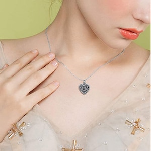 Puede incluir: Un collar de plata con un colgante en forma de coraz&oacute;n con un dise&ntilde;o floral detallado. El colgante est&aacute; abierto y se puede usar como un medall&oacute;n.