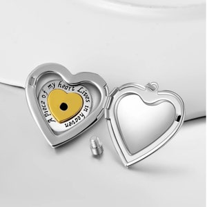 Puede incluir: Un medall&oacute;n de coraz&oacute;n plateado con un coraz&oacute;n de oro m&aacute;s peque&ntilde;o en el interior. El medall&oacute;n tiene la inscripci&oacute;n "A piece of my heart Lives in Heaven" en el exterior.