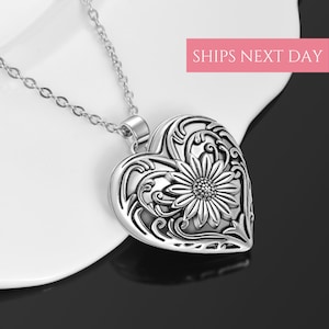 Puede incluir: Collar de plata con dije en forma de coraz&oacute;n con un dise&ntilde;o floral adornado con un girasol en el centro.