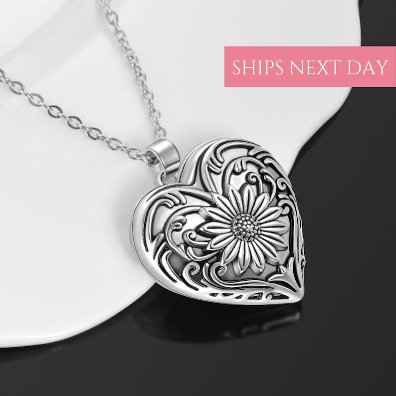 Puede incluir: Collar de plata con dije en forma de coraz&oacute;n con un dise&ntilde;o floral adornado con un girasol en el centro.