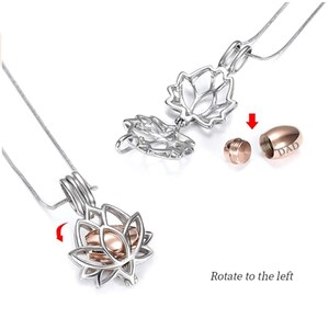 May include: A silver-colored lotus flower pendant necklace with a rose gold urn inside. The pendant opens to reveal the urn, which is engraved with the word "DAD". The necklace is displayed on a white background.