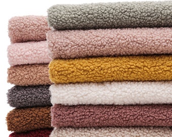 May include: A stack of ten different colored faux fur fabric swatches. The colors are gray, pink, yellow, white, pink, brown, gray, brown, red, and beige.