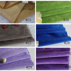 May include: Close-up of six fabric swatches in different colors. The swatches are folded in half and arranged in two rows of three. The colors are beige, green, gray, blue, purple, and lavender.